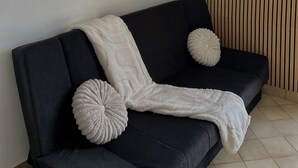 A modern living room with a black sofa, a white throw blanket, and decorative woven wall hangings. - Accommodation in a small character house in SAINT GENIES (Saint-Geniès)