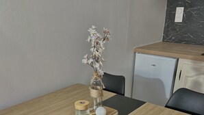 A dining table with a black and beige table runner, a glass jar with flowers, a candle, and a jar with a lid. - Accommodation in a small character house in SAINT GENIES (Saint-Geniès)