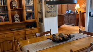 Et træspisebord med stole, et skilt med teksten "COTTAGE LIFE" og et skilt med "CALM IT'S A WONDERFUL LIFE".