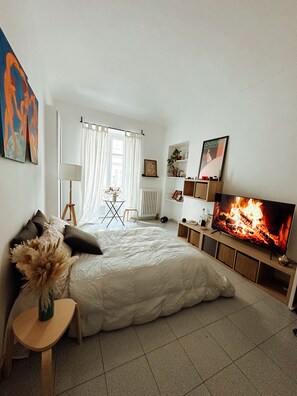 A modern bedroom with a large bed, a TV, a fireplace, and a small table. - Bright open space in the center of Turin (Torino)