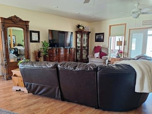 A living room with a sectional sofa, a television, a cabinet, and a mirror.