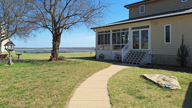 Ein Haus mit überdachter Veranda, einem Weg zum Eingang und Blick auf die Landschaft.