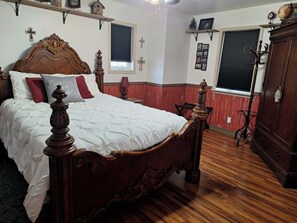 Een kamer met een houten bed, een houten kledingkast en een raam met uitzicht.