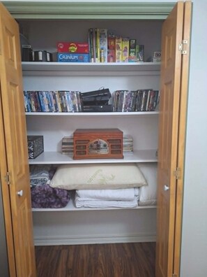 Un placard avec des étagères contenant des livres, des DVD et une radio.