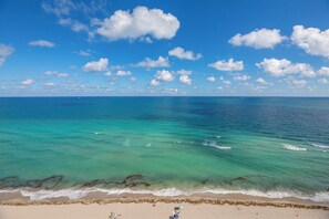 A beach with clear turquoise water, a sandy shore, and a clear sky with clouds. - Stunning Penthouse on Hollywood Beach (Hollywood)