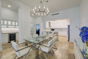 A modern kitchen with white cabinets, a glass dining table, and a chandelier. - Stunning Penthouse on Hollywood Beach (Hollywood)