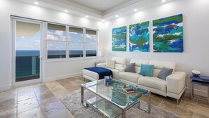A modern living room with a glass coffee table, a white sofa, and abstract paintings on the wall. - Stunning Penthouse on Hollywood Beach (Hollywood)