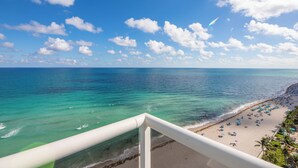 A beach with clear turquoise water, a sandy shore, and a white railing. - Stunning Penthouse on Hollywood Beach (Hollywood)