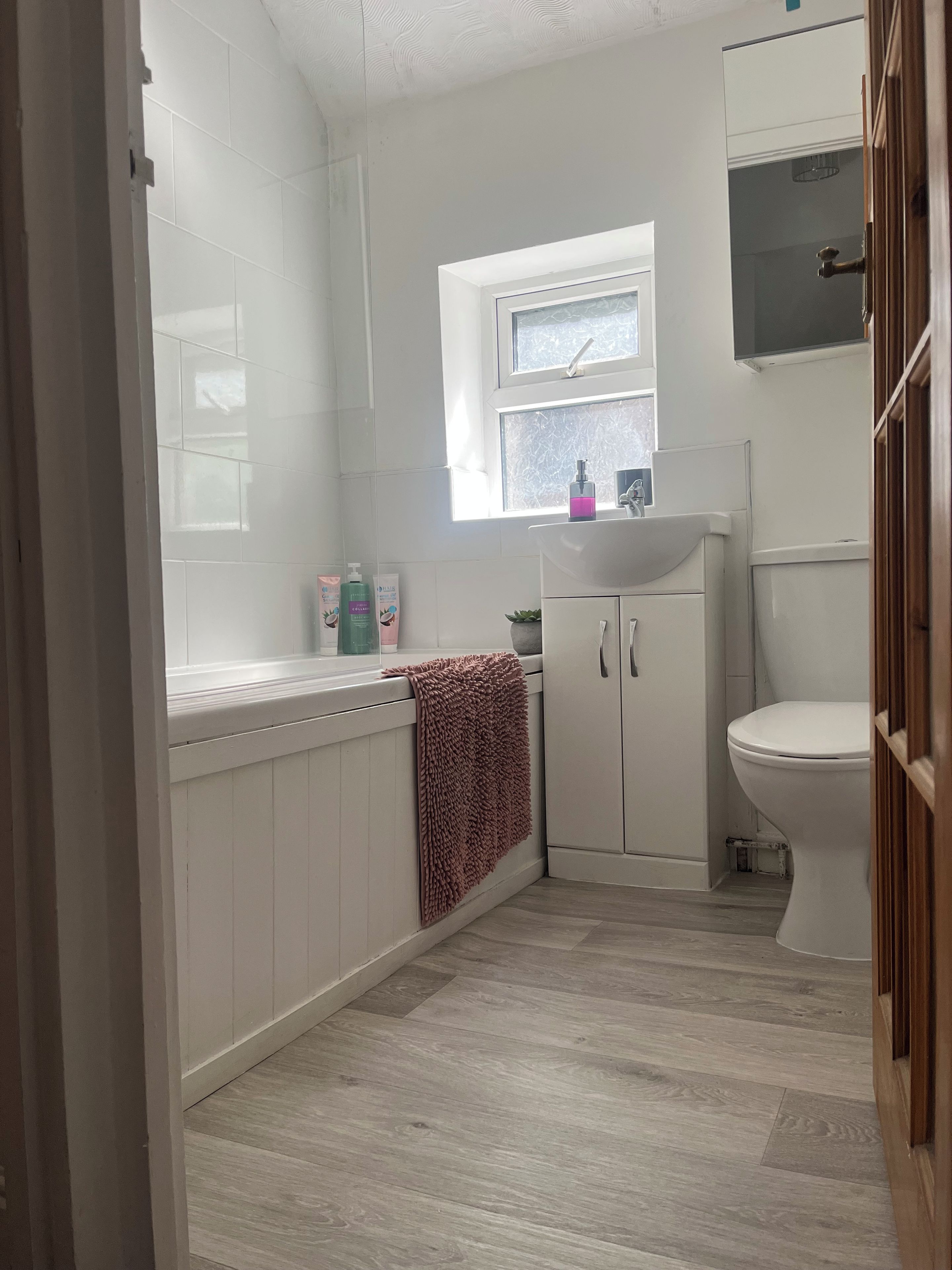 A bathroom with a white sink, a toilet, and a window.