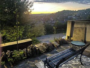 A bench with a patterned mat, a stone wall, and a view of a town at sunset. - Chestnut lodge-escape to the woodland near the city! (Bradford)