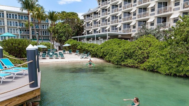 Ein Hotelpoolbereich mit klarem Wasser, Liegestühlen und einem Gebäude mit mehreren Balkonen.