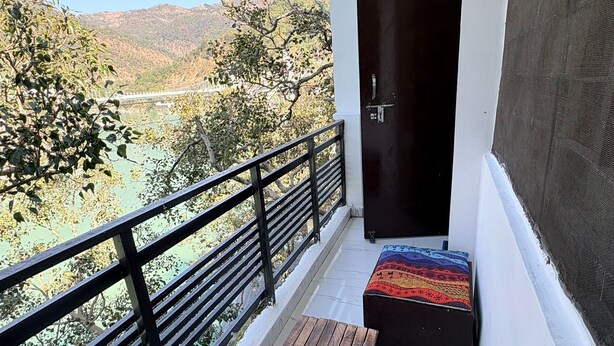 A balcony with a wooden bench and a colorful rug, overlooking a mountainous landscape.