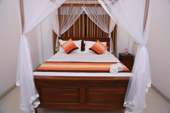 Una cama con estructura de madera, ropa de cama blanca y dos almohadas con estampados a rayas.