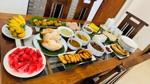 Een eettafel met diverse gerechten, waaronder fruit, hapjes en sausjes.
