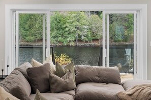 A living room with a large window overlooking a body of water and greenery. - Charming Riverside Retreat in the Heart of Huntsville (Huntsville)