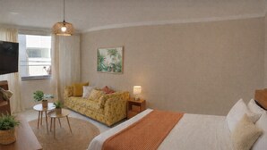A hotel room with a bed, a sofa, a small table with a plant, a lamp, and a painting on the wall.