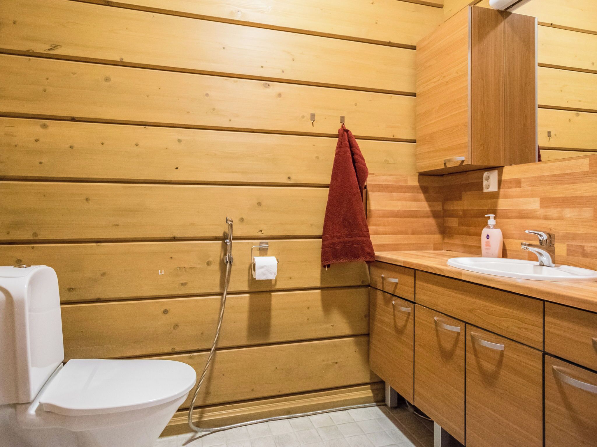 Un baño con paneles de madera, un inodoro, una ducha y un lavabo con armarios de madera.