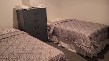 A hotel room with two beds, a dresser, and a painting on the wall.