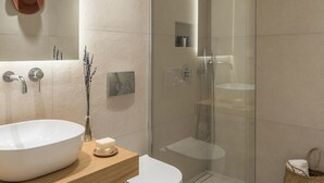 Ein modernes Badezimmer mit einem großen, weißen Waschbecken, einer gläsernen Dusche und einem Holz-Waschtisch.