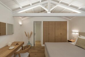 Une chambre avec un bureau en bois, un lit, une armoire et un miroir.