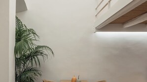 Ein Essbereich mit Holztisch und -stühlen, einer Topfpflanze und einer Treppe mit Holzwandung.