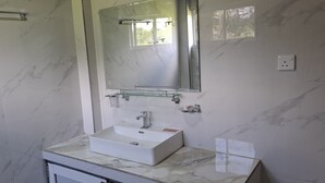 Une salle de bain avec un lavabo en marbre, un miroir et une étagère en verre.
