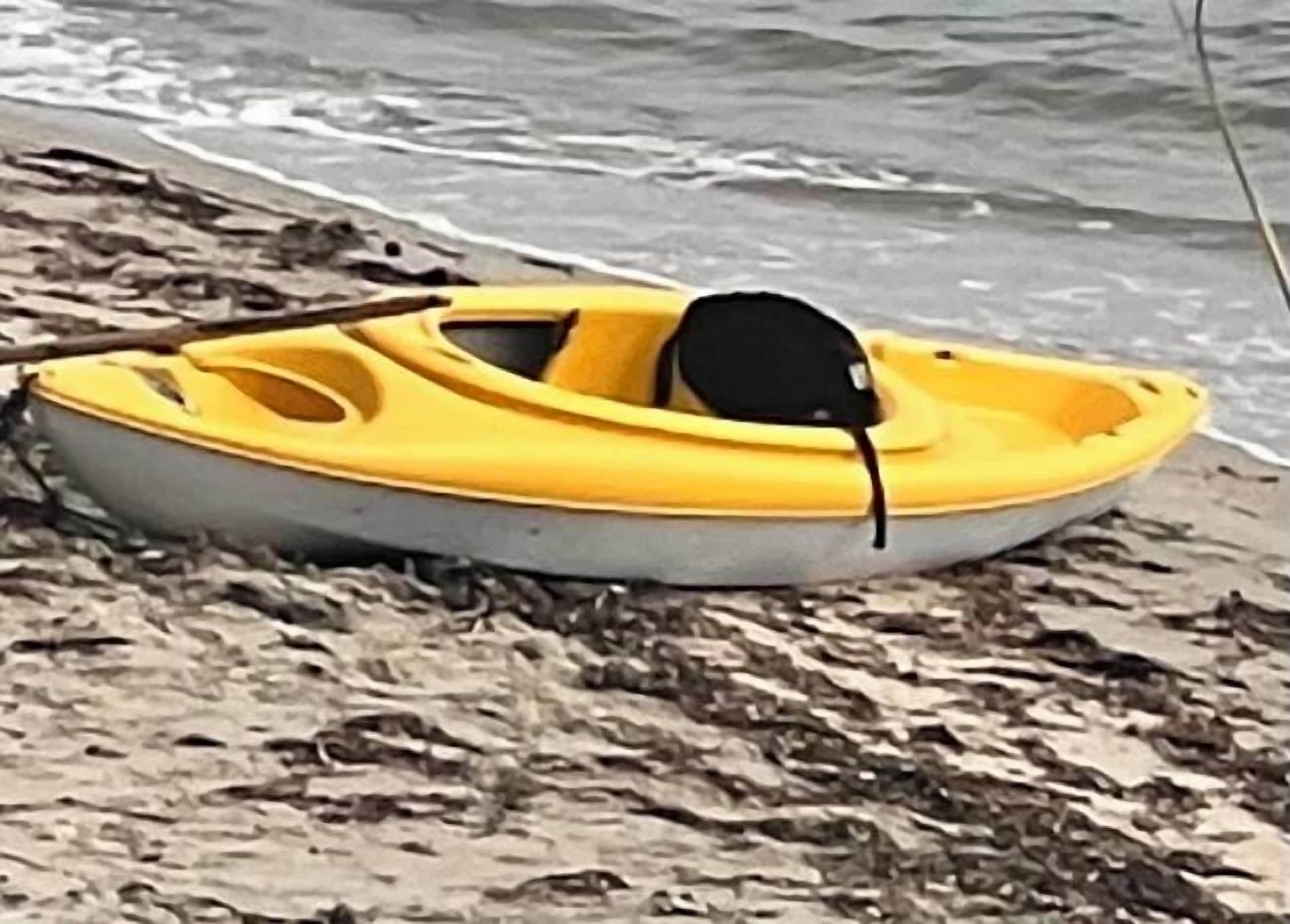 Un pequeño bote amarillo sobre una playa arenosa.