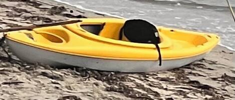 Un petit bateau jaune sur une plage de sable.