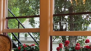 A window with a view of a tree and red flowers.