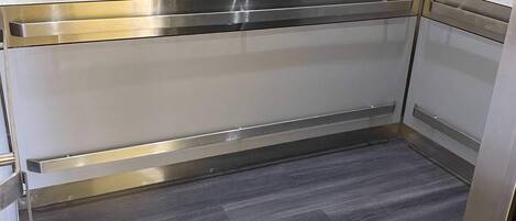 Un ascensor moderno con paredes metálicas y suelo gris.