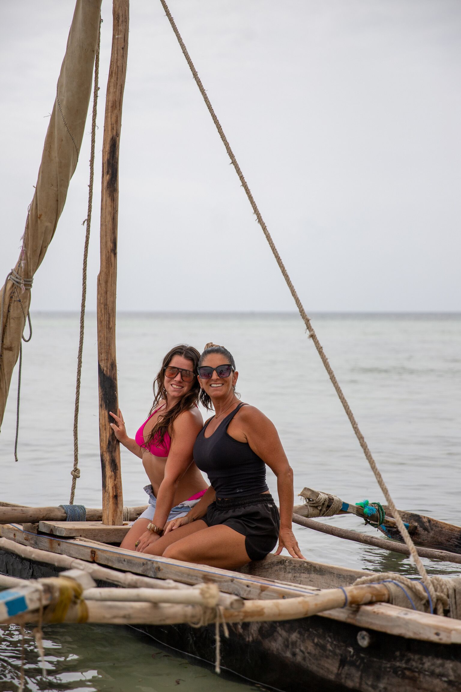 Dos personas sentadas en un bote de madera con cuerdas y una cuerda atada a un mástil.