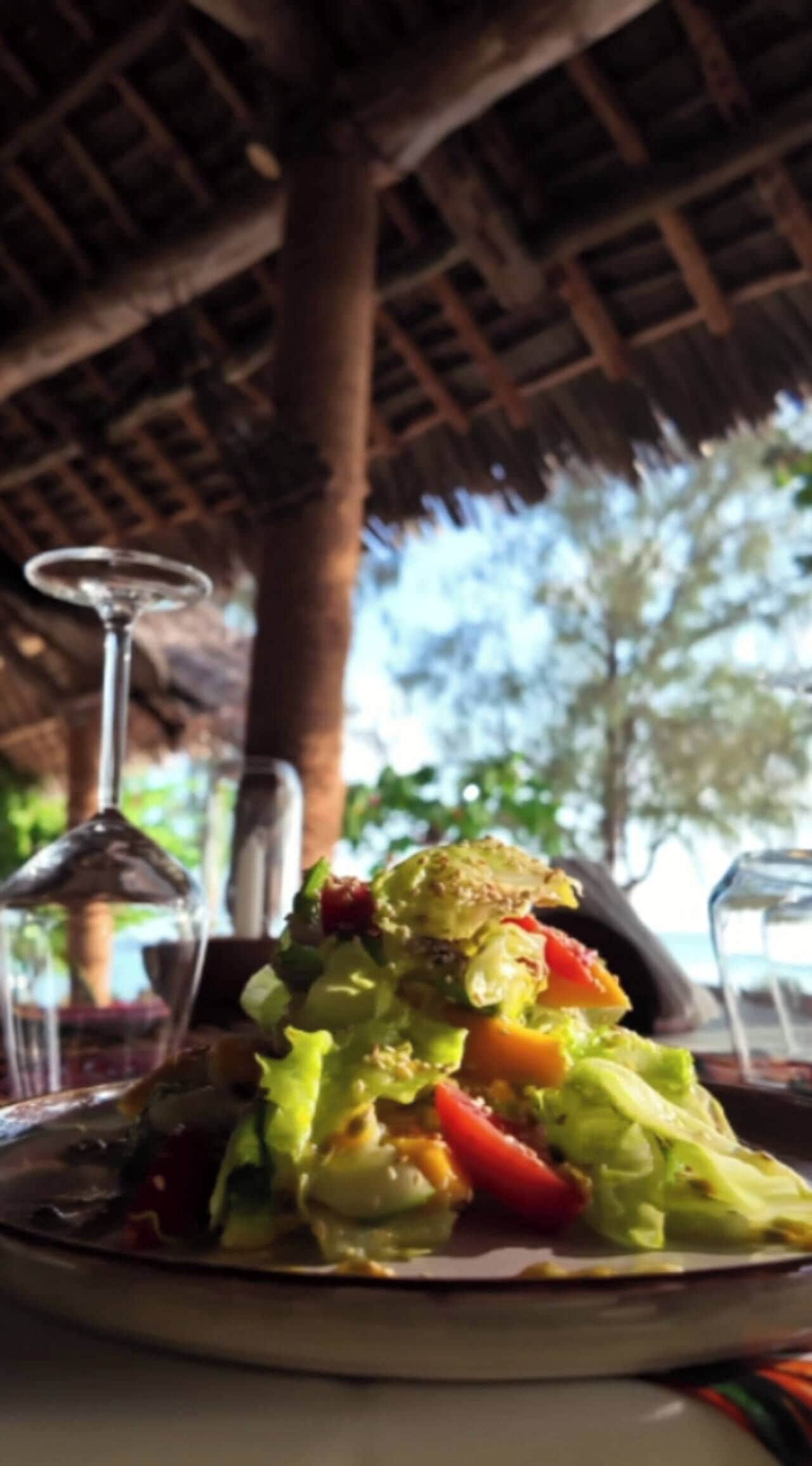 A table with a salad, a glass of water, and a glass of wine.