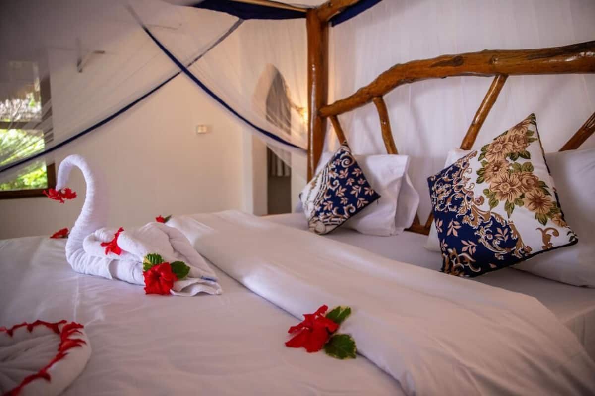 Una cama con ropa de cama blanca, almohadas decorativas y un cabecero de madera.