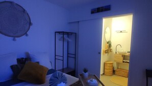 A bedroom with a bed, bedside table, and a view into the bathroom. - A sunny interlude (Galargues)