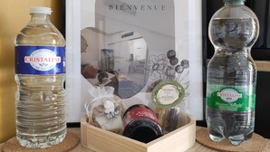 A framed welcome sign, two bottles of Cristaline water, and a wooden box with a bottle of wine and a jar of jam. - A sunny interlude (Galargues)