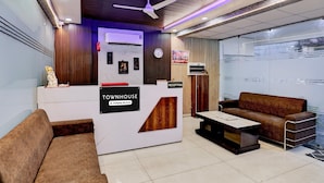 Zona de recepción con mostrador, un reloj, televisor y sofá.