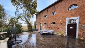 Un bâtiment en briques doté d’un patio couvert, d’un espace extérieur aménagé pour s’asseoir et d’une porte.