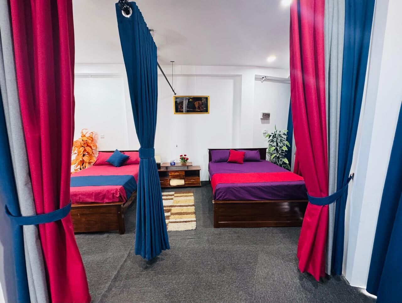Une chambre avec deux lits, chacun recouvert d’une couvre-lit d’une couleur différente, une chaise suspendue et des rideaux.