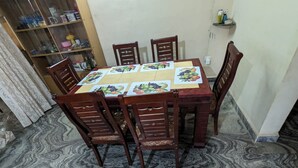 A dining table with a marble-patterned floor, surrounded by wooden chairs. - A 2 bedroom villa, with full self catering kitchen set in a quaint Goan village. (Navelim)