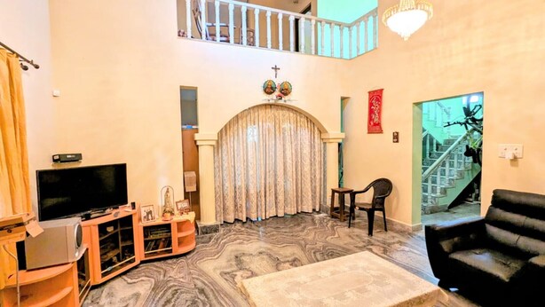 A living room with a TV, entertainment unit, and a staircase leading to an upper level. - A 2 bedroom villa, with full self catering kitchen set in a quaint Goan village. (Navelim)