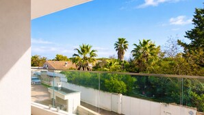 Un balcón con vista despejada a una zona residencial, con casas y palmeras.