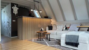 A modern loft bedroom with a sloped ceiling, a white sofa, a patterned rug, and a wooden coffee table. - Das-Bergheim.de A stylish vacation home in Chiemgau! (Siegsdorf)