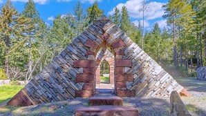 Un arco de piedra que da paso a una zona boscosa.