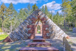 A stone archway leading to a forested area. - Mendocino Stone Ranch Compound, by Vinifera Homes (Anchor Bay)