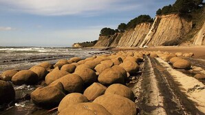 Una playa con grandes rocas y un acantilado.