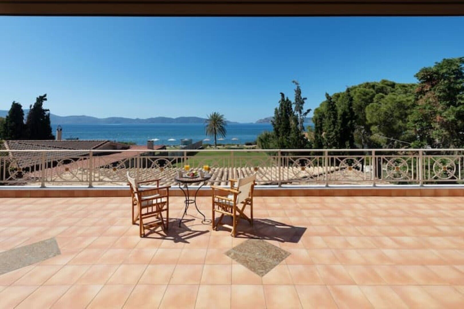 Une terrasse avec une table et des chaises, offrant une vue panoramique sur la mer et les montagnes.