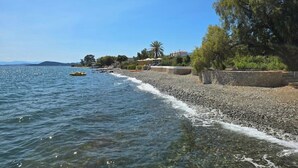 A pebble beach with clear water, a few boats, and buildings in the background. - Private Beachfront Villa, Experience beauty, luxury and serenity, all in one. (Θερμησία)