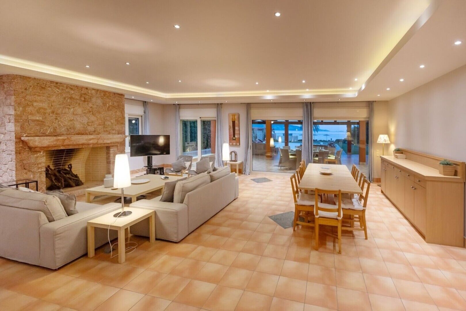 A spacious living room with a fireplace, a TV, and a dining area with a large table and chairs.