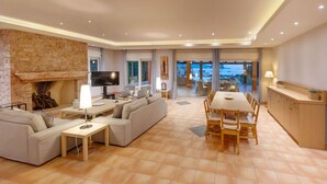 A spacious living room with a fireplace, a TV, and a dining area with a large table and chairs. - Private Beachfront Villa, Experience beauty, luxury and serenity, all in one. (Θερμησία)