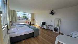 A hotel room with a large bed, a TV, a desk, and a mirror.